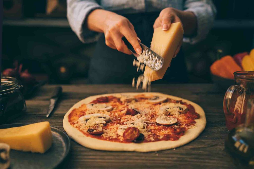 Chef adding cheese to a pizza