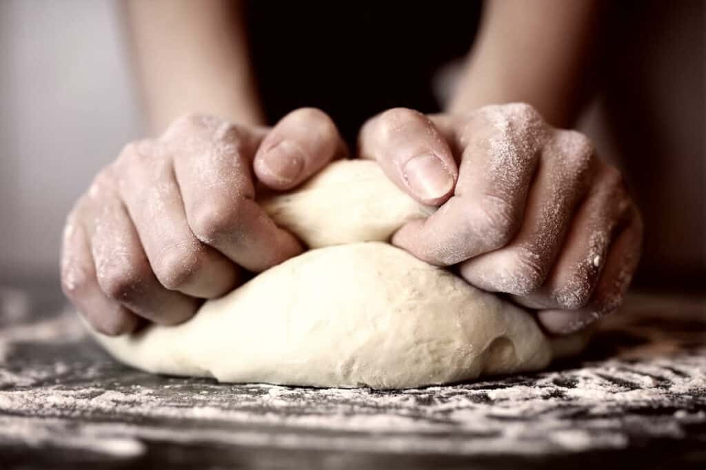 A chef pulling dough to make pizza