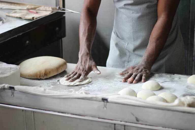 A man off-screen rolling dough for baking