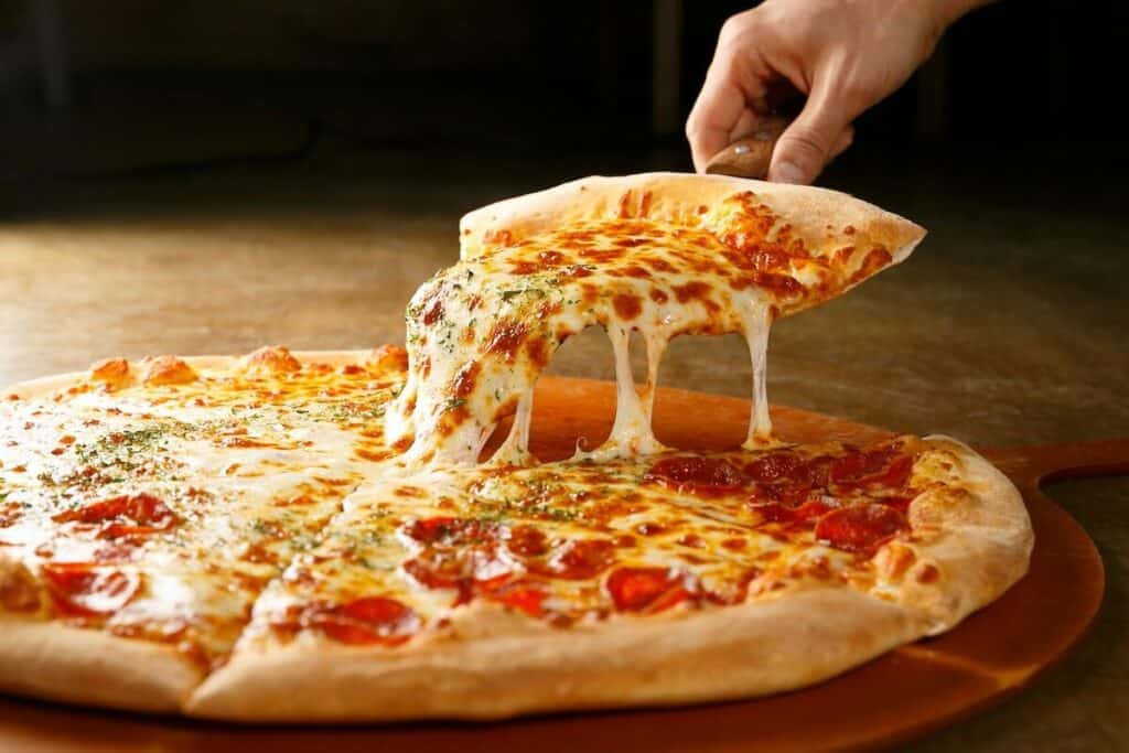 A person pulling a cheesy slice