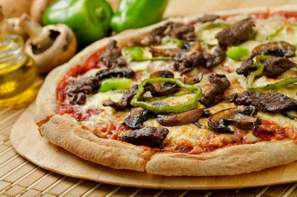 Pizza topped with cheese, mushrooms, and vegetables