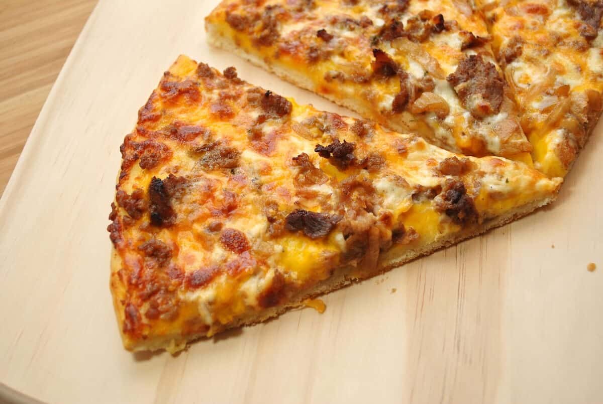 Three slices of steak pizza on a pizza stone