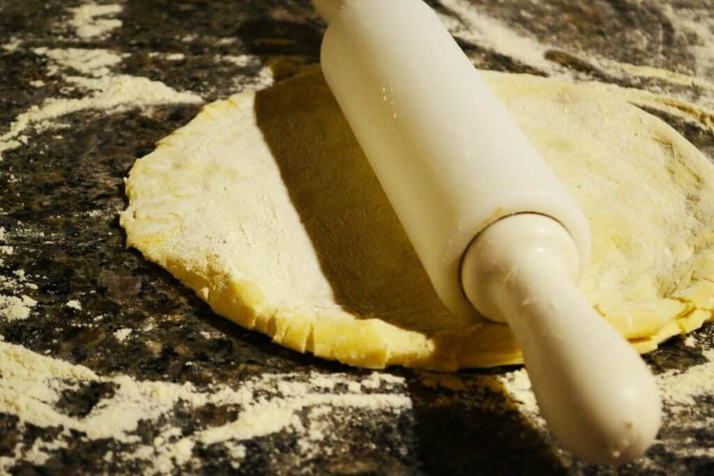 A rolling pin sitting on some pizza dough