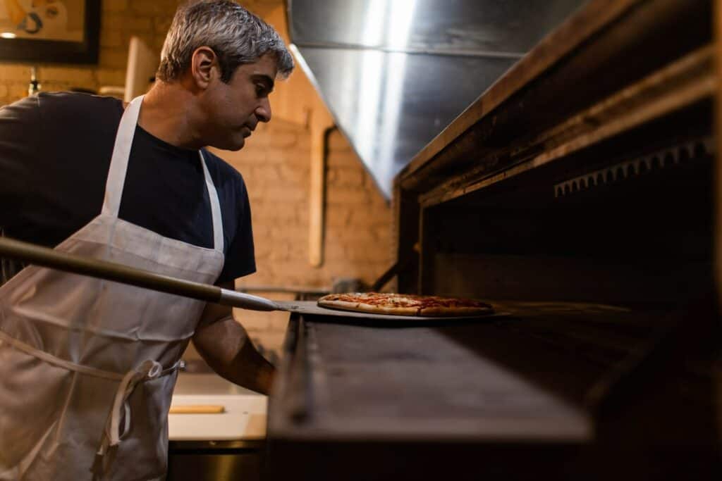A pizza chef making pizza in a special oven