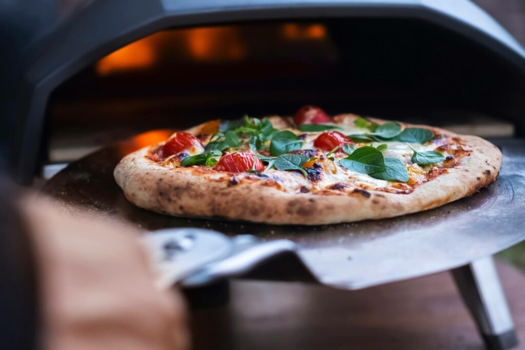 A person is placing a pizza in a pizza oven