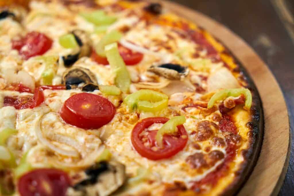 A pizza with a rich topping with tomatoes and peppers