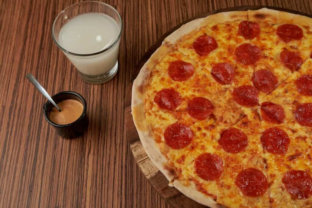 Pepperoni pizza next to two cups