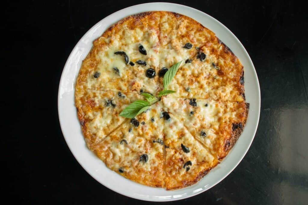 Pizza with black olives on a ceramic platter