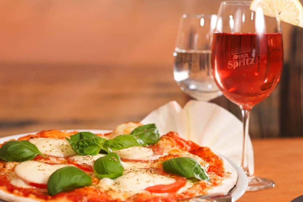Pizza with mozzarella cheese next to a glass of wine