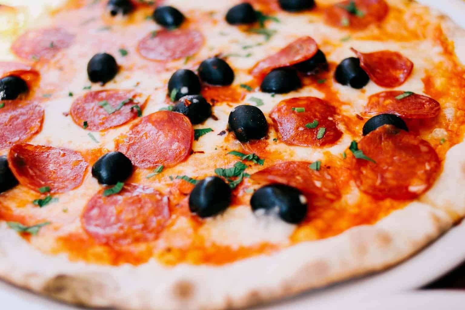 Pizza with pepperonis and black olives