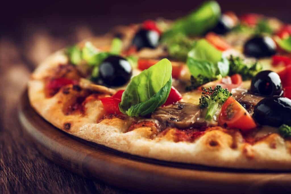 Baked thin-crust pizza on a wooden platter