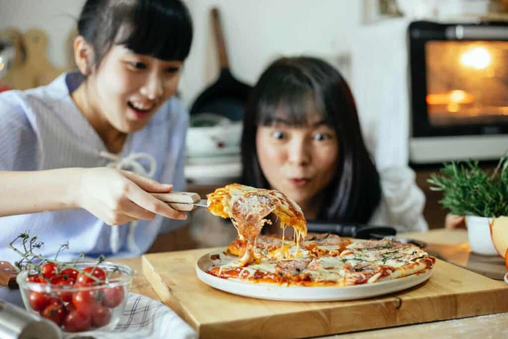 Joyful women looking at a slice of pizza