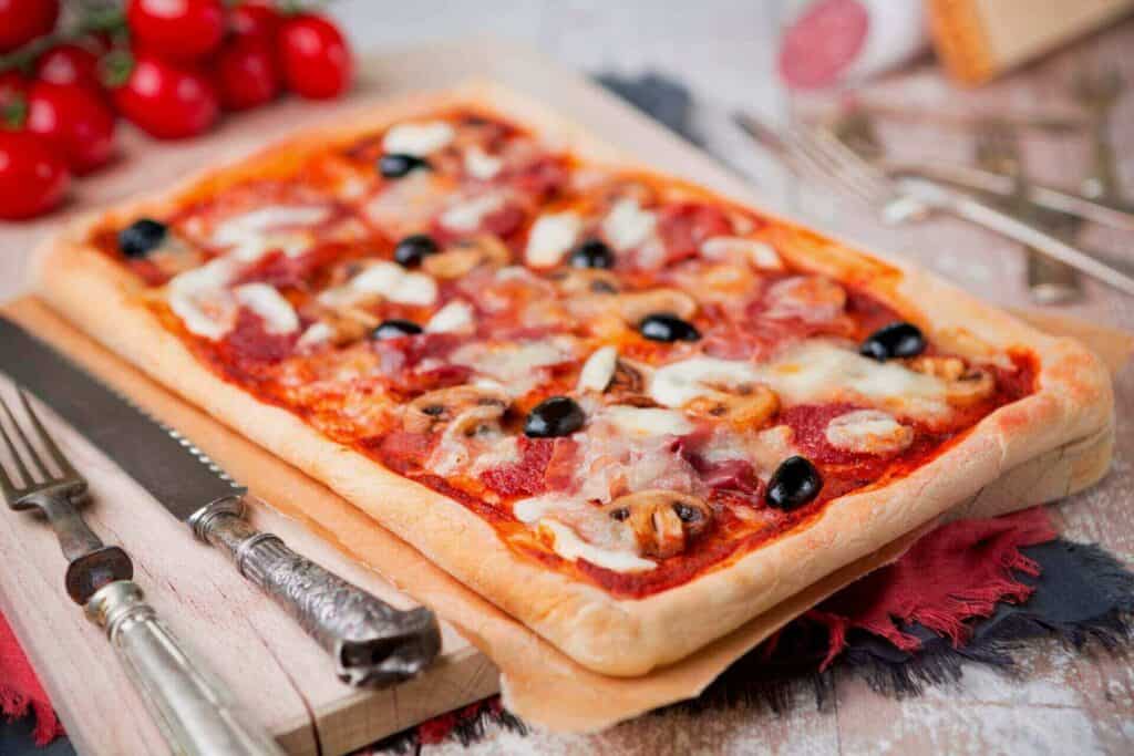 A rectangular pizza next to a plate