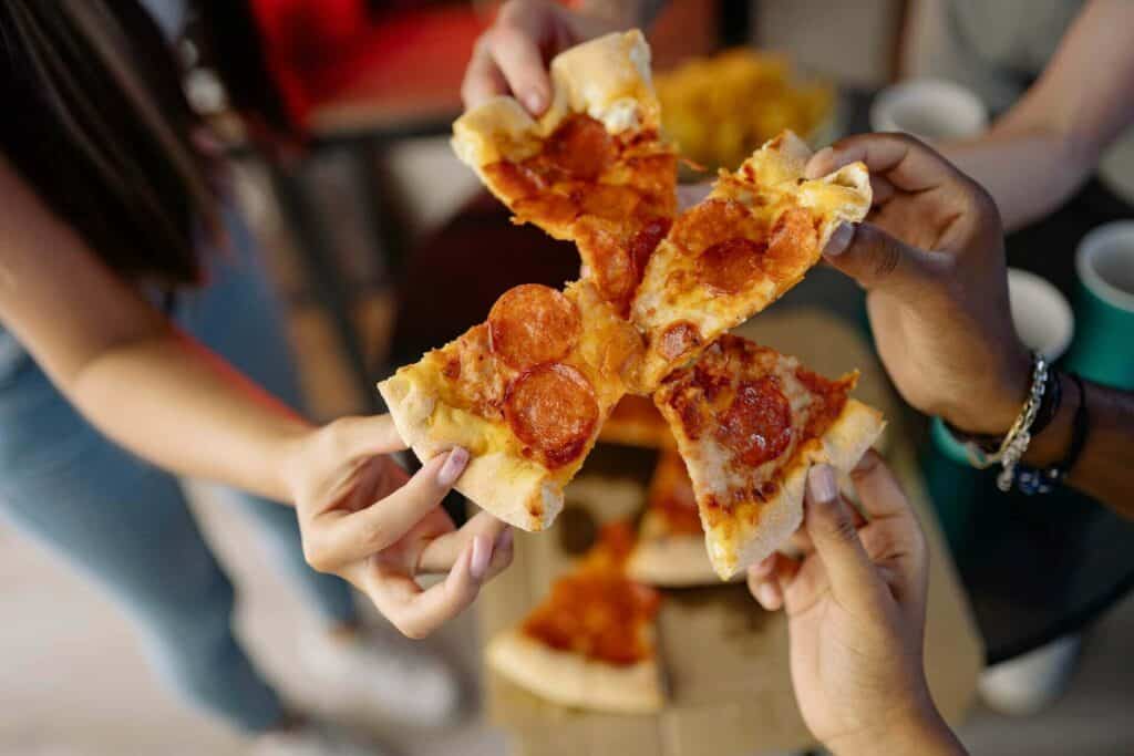 People holding pizza slices